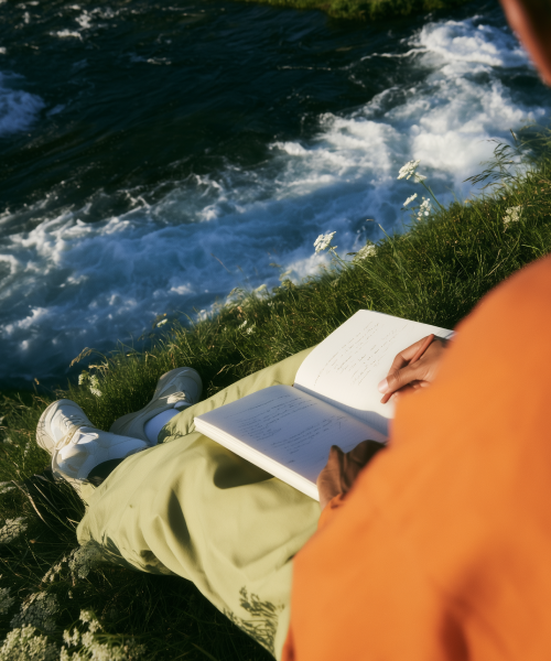 Person writing field notes beside a river